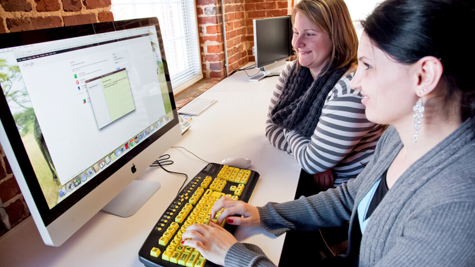 Two women using a computer with a high contrast keyboard